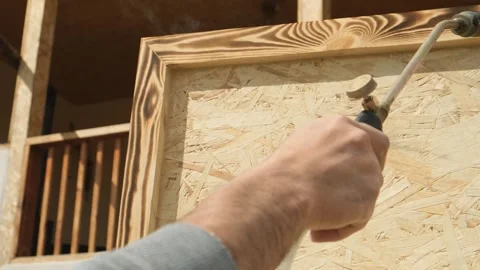 Mans hand holding gas torch using flame to burn newly made wooden furniture piec Stock Footage 332875454
