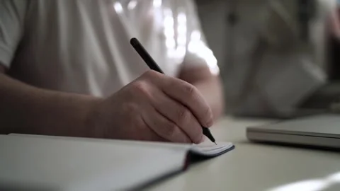 Mans Hand Holding a Pen While Writing on a Notebook. Journaling his thought.. Видео 306064819