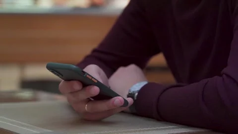 Mans hand holding smartphone on a table, everyday moment in a cafe Stock Footage 294627911