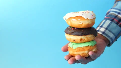 Man's hand holding stack of fresh donuts close up Stock Footage 146014612