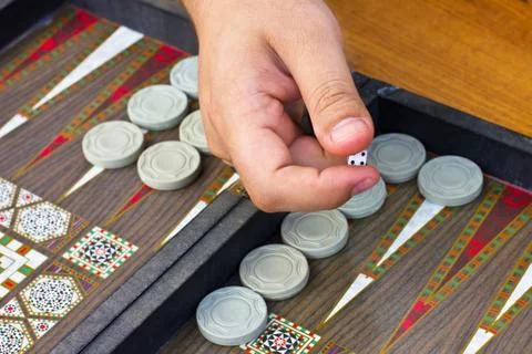 A man's hand holds a backgammon game Stock Photos