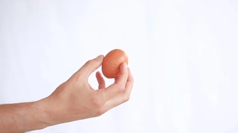 Man's hand holds a chicken egg on a white background Stock Footage 75807105