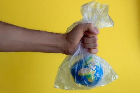 A man's hand holds the globe in a plastic transparent bag Stock Photos