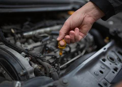 A man's hand holds the lid. checking the oil level. Stock Photos