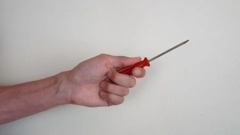 A man's hand holds a screwdriver with a red handle, pointing the tip to the.. Vidéo 318214111