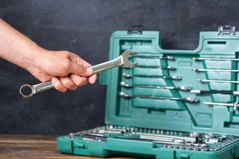 A man's hand holds an spanner on the background of an open suitcase with an a Stock Photos