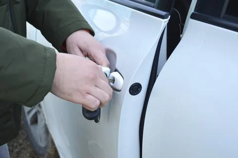 A man's hand inserted the key and slightly opened the car door Foto stock
