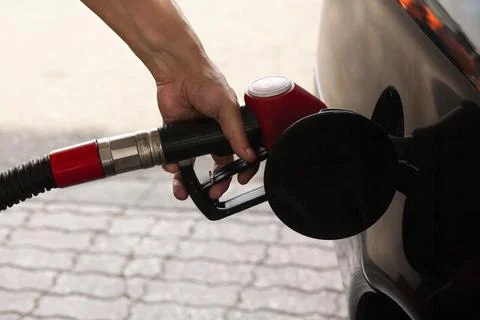 Man's hand is inserting a gas pump nozzle in a fuel tank, Car refueling on th Stock-Fotos