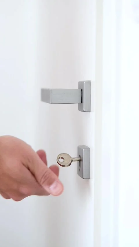 Man's hand inserting a key into a keyhole, turning it and opening a door Stock Footage 280003833