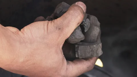 Man's hand inserting pieces of charcoal into a barrel for roasting Video stock 154214987