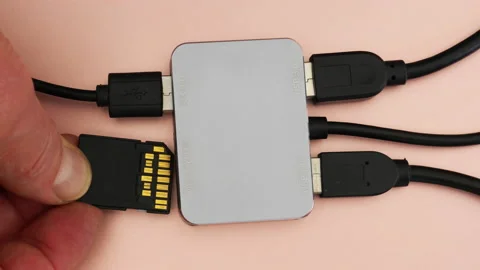 Man’s hand inserting a secure digital SD card into a multiport computer adapter. Stock Footage 221243011