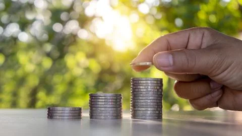 Man's hand inserting a silver coin into a coin Finance, Business, Investmen.. Stock Photos