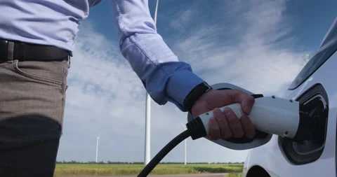 Man's hand inserts the charging plug of an electric car into the charging socket Stock Footage 168493638
