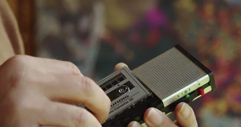 A man's hand inserts a microcassette into a retro handheld tape recorder Video stock 201246913