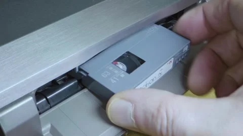 A man's hand inserts a mini DV cassette into a silver-colored DV tape recorder Video stock 297800864