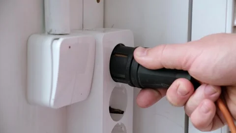 A mans hand inserts a plug into an outlet. Safety engineering. White plastic Stock Footage 321861314