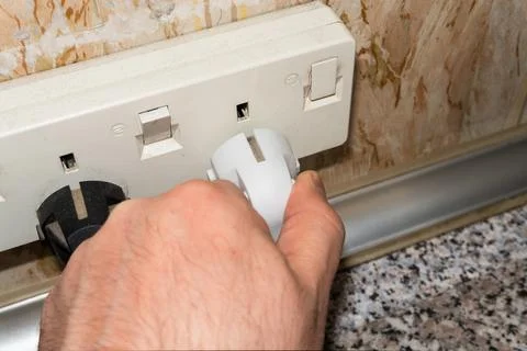 A man's hand inserts a plug into a socket. Sockets in the wall, wires in the Stock Photos
