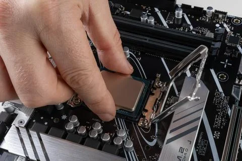 A man's hand installs a new processor into an motherboard socket close-up Stockfoto's