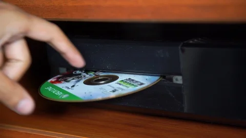 Man's hand introducing Xbox game disc in console Vidéo 105133131