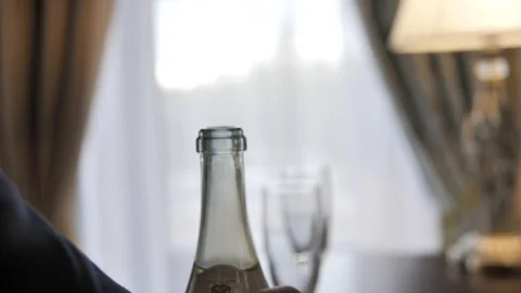 A man's hand jacket pours sparkling wine from a bottle into a wine glass.  Video stock 106191047