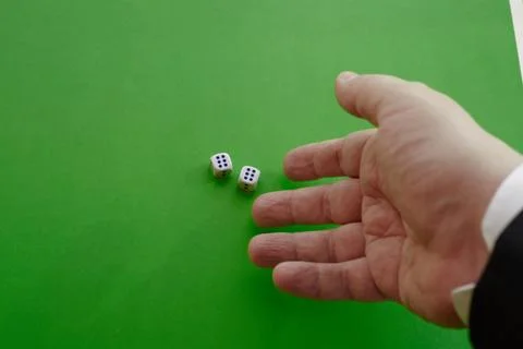 A mans hand in a jacket throws two dice on a green cloth, two winning dice, t Stock Photos