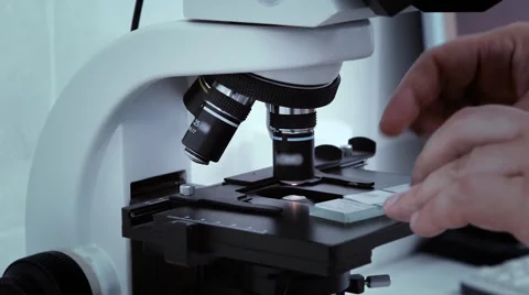 Man's hand laboratory scientist set glass slide in the microscope for analysis Stock Footage 65826626
