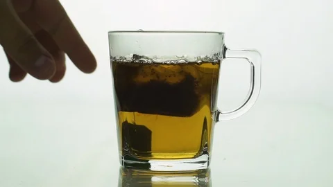 Man’s hand lifting and dropping black tea bag into glass transparent mug to Stock Footage 129444944