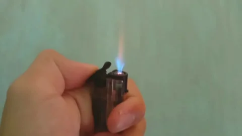 A man's hand lighting a gas lighter indoors. Stock Footage 322985824