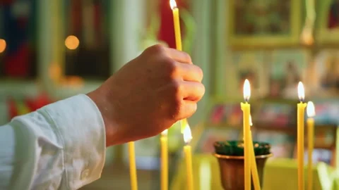 A man's hand lights a candle in the Temple of the Lord. Christian faith in God. Stock Footage 248376389