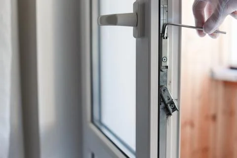 Man's hand makes adjustment of hardware of the uPVC door mechanism with an allen Stock Photos