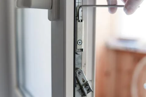 Man's hand makes adjustment of hardware of the uPVC door mechanism with an allen Stock Photos