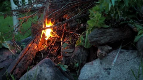 A man's hand makes a fire by putting branches on the fire Stock Footage 166776812