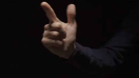 Man's hand makes a gun or pistol gesture on a dark background fires one time Stock Footage 132260836