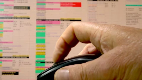 Man's hand mouse scrolling through a spreadsheet on a computer monitor. Stock Footage 200879953