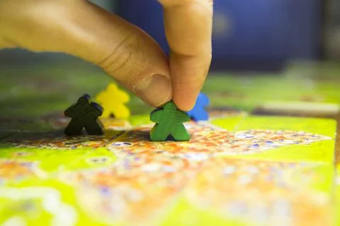 Man's hand moves the chips in the board game carcassonne Stock Photos