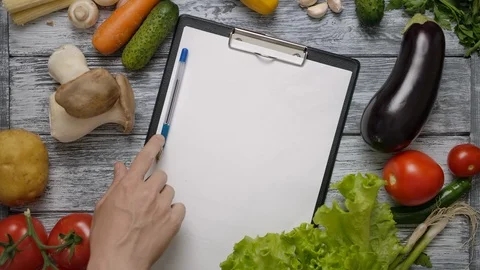 The man's hand moves the pen on the notepad on a wooden table Stock Footage 121483920