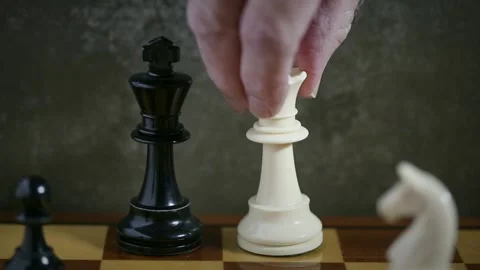 Man's hand moves white queen beside black king, winning the chess game with c Stock Footage 186604480