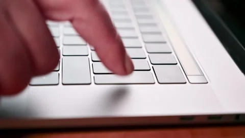 A man's hand multiple times presses the enter button on a laptop. Work at home Stock Footage 154005323