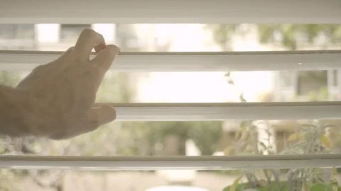 Man’s hand opening window shutters and looking out. Stockbeeldmateriaal 129115301