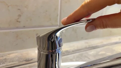 The man's hand opens and closes the shiny metal valve from the water tap Stock Footage 164075450