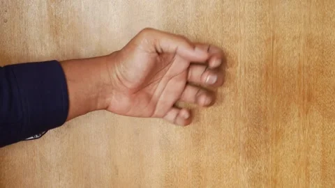 Man's hand opens and closes on a wooden surface in a dynamic clip, showing .. Stock Footage 332745631
