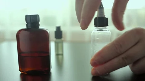 Man's hand opens a bottle for a liquid for e-cigarette for background. Stock Footage 72414720