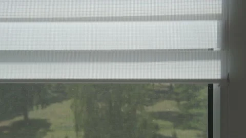 A man's hand opens the day-night blinds on a window. Video stock 183265019