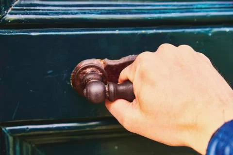 A man's hand opens the door, a close-up photo. The hand holds onto the antiqu Stock Photos