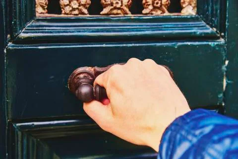 A man's hand opens the door, a close-up photo. The hand holds onto the antiqu Stock Photos
