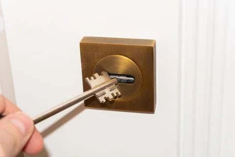 A man's hand opens a door lock with a key, door lock repair, handyman or lock 스톡 사진
