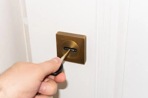 A man's hand opens a door lock with a key, door lock repair, handyman or lock Stock Photos
