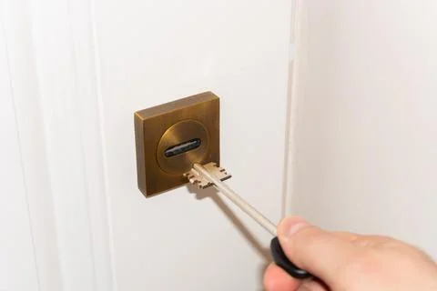 A man's hand opens a door lock with a key, door lock repair, handyman or lock 스톡 사진