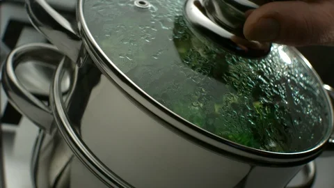 Man's hand opens a double boiler and shows green cooked broccoli Stock Footage 113605520