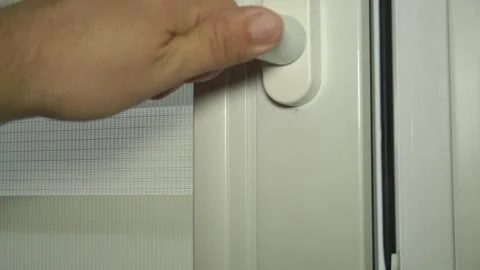 A man's hand opens the sash of a plastic window with roller blinds Video stock 247833469